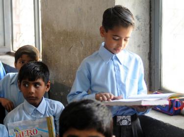 Umair, reads from a book in the classroom. Pakistan. Credit: 